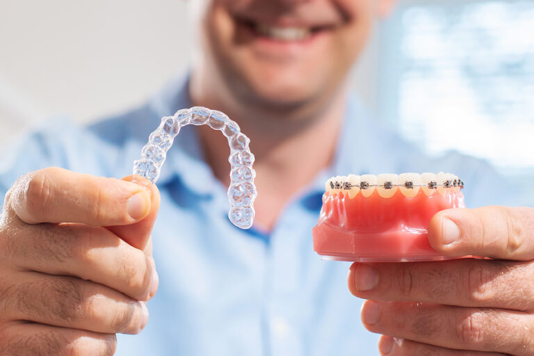 Dental Care.smiling Orthodontist Doctor Holding Aligners And Bra